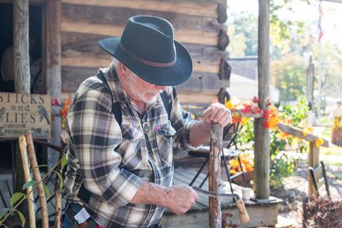 Jeff Blackwell carves into a cane during Clarkesville History Harvest on Saturday. His passion is woodworking, which he says brings him peace. ZACH TAYLOR/Staff