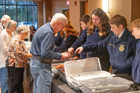 Farm Bureau Board Member Danny Brooks is served a hot meal from Crossroads Cafe by Habersham County FFA’s Aydan Savage. ZACH TAYLOR/Staff