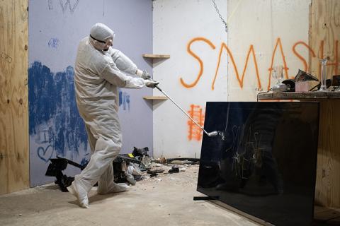 Christopher Davidson breaks an old television with a golf club in one of Smash It’s several “smash rooms.” JULIANNE AKERS/Staff