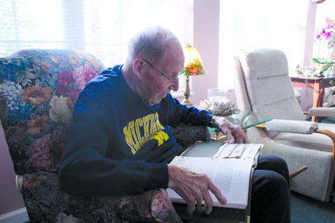 Ken Schubring flips through photographs documenting the bombing at Pearl Harbor, as well as his own account of his service in Hawaii and beyond. HANNAH CAUDELL/Staff