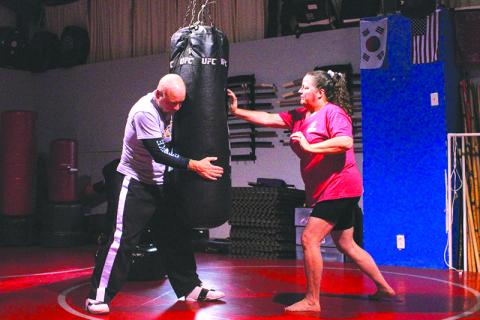Bobby Popham (left) holds a punching bag while Ellie Van Doornum (right) strikes with her right palm against the tough fabric. HANNAH CAUDELL/Staff