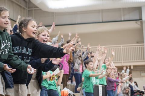 TFS Students Allegra Perry, Piper Prince and Riley McCracken cheer on the Piedmont Lions and reach to catch pom-poms and bouncy balls given away at the game. JULIANNE AKERS/Staff