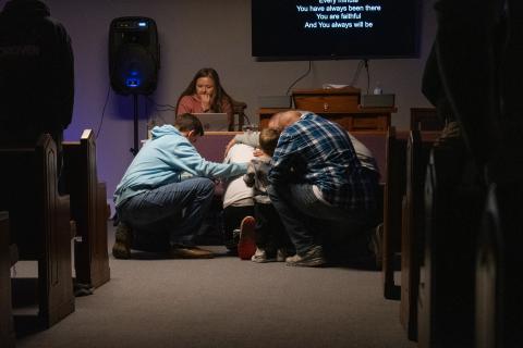 Some men of the church come before the altar to pray, and their fellow church goers follow to lay hands in support.  HANNAH CAUDELL/Staff