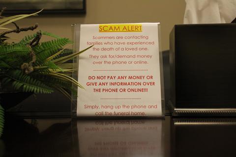 A scam alert sits in the conference room at McGahee-Griffin & Stewart Funeral Home, meant to warn incoming families of the scam calls that have been plaguing the North Georgia area for a little over a year. HANNAH CAUDELL/Staff