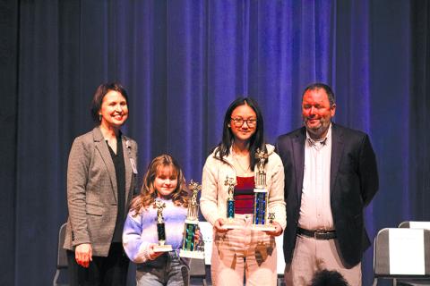 From left, Director of Elementary Schools Dr. Susan Davis,  Woodville Elementary School student Wiley Colston, Hilliard A. Wilbanks Middle School student Khamla Laosalie, and  Assistant School Superintendent Patrick Franklin stand on the stage after the Habersham County School System spelling bee competition for photos. Laosalie won first prize after multiple rounds, and Colston earned the runner-up spot. HANNAH CAUDELL/Staff 