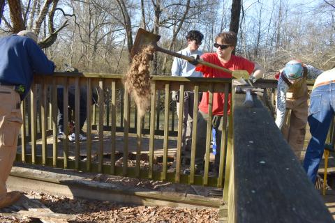 Cal Osborne shovels out dirt that’s collected under the boardwalk so he and his team of scouts and scout leaders can begin repairs on the boardwalk. SAMANTHA SINCLAIR/Staff