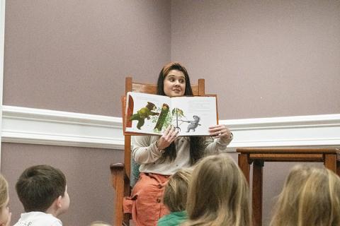 Amanda Almazan, the Clarkesville Library’s youth services coordinator, takes a seat in the rocking chair amongst the children sitting at her feet to read this year’s pick for the featured title, Wombat Said Come In by Carmen Agra Deedy. HANNAH CAUDELL/Staff