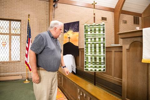 Pastor Randy Kanipe shows the weaving banner in the sanctuary. The weaving banner is a display of more than 130 pieces of fabric brought by an individual from the now mixed congregation, showcasing unity as one church body. ZACH TAYLOR/Staff
