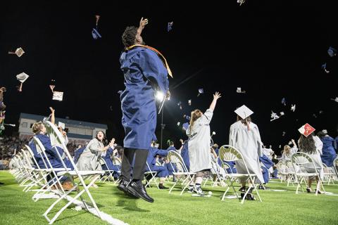 Kendall Respress leaps into the air as he throws his graduation cap with other graduates. ZACH TAYLOR/Staff