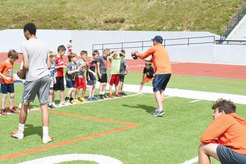 Coach Tate Gailey instructs campers in a wide receiver drill in 2023.