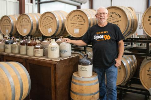 Owner Andy Sudderth stands next to barrels full of whiskey in the new distillery in Mt. Airy, his hand resting on a ceramic jug from the R.M. Rose Distillery in Atlanta in the late 1800s. ZACH TAYLOR/Staff