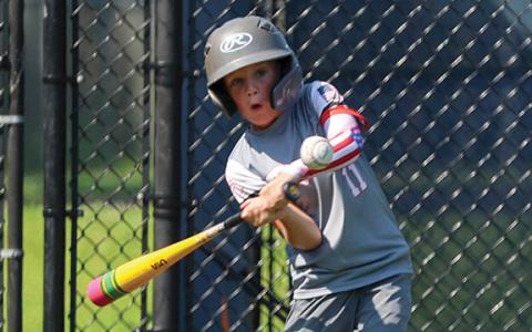 Camper Krew Trusty hits the ball with his pencil-themed bat during the baseball camp on Wednesday, June 25 at Raider Park. (LANDEN TODD/Staff)
