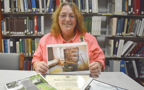 Lynn McCollum holds a photo of the display of Dr. Bodo Otto’s tools at the Old Barracks Museum in Trenton, N.J. Her certificate of membership for the National Daughters of the American Revolution is surrounded by photos and documents sharing some of the history of her Revolutionary War ancestors. (Samantha Sinclair/Staff)