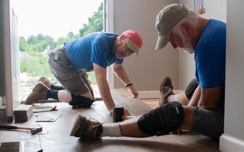 From left, Todd Valentini and Richard Price help each other put flooring in at House 81, one of the few homes Habitat for Humanity is building on the same property. (Hannah Caudell/Staff)