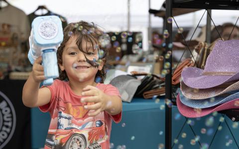 Wyatt Swain blows bubbles at the camera while waiting at a booth at the Big Red Apple Festival in Cornelia. (Zach Taylor/Staff)