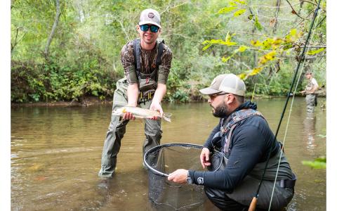 Jackson Savage holds a fish after being guided by Seth Underwood during the fly fishing festival on Sunday. (Zach Taylor/Staff)
