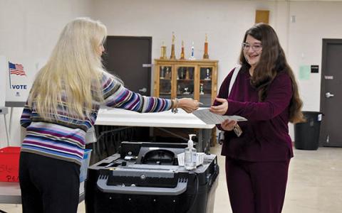 Demorest Precinct Poll Worker Sonya Frady hands Megan Zimmerman a voter sticker after voting Tuesday morning. (Samantha Sinclair/Staff)