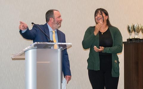 Emely Martinez (right) laughs while Superintendent Patrick Franklin asks Martinez’s family to stand up for an applause from the audience, commending them as well for their daughter’s hard work. (Hannah Caudell/Staff)
