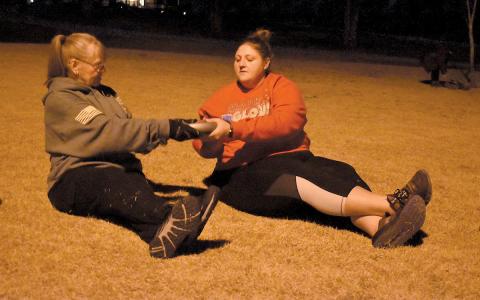 Janice “Buttercup” Gilbert and Brittany Washington pass a weight at one workout station. (Samantha Sinclair/Staff)