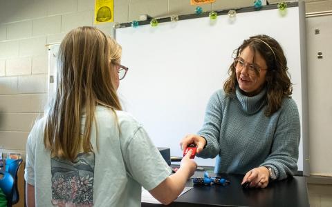 Discovery Teacher Hannah DeMore hands a lock to one of her students, who wishes to see if she broke the code during a class exercise. (Hannah Caudell/Staff)