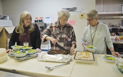 Kitchen volunteers Kim Finley, Claudia Jessup and Tina Hatcher prepare meals for the guests at the warming center Monday night. (Samantha Sinclair/Staff)