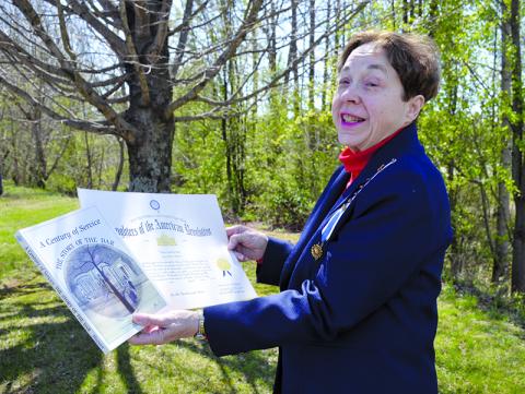 Delores Anderson shows her Daughters of the American Revolution membership certificate and her copy of A Century of Service: The Story of DAR. The year she joined was the centennial year of the society. Samantha Sinclair/Staff