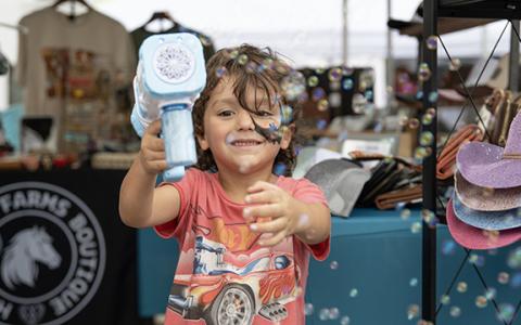 Wyatt Swain blows bubbles at the camera while waiting at a booth at last years Big Red Apple Festival. (File)