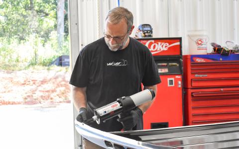 Tommy Dalton, a trainer at W&W Collision Center, prepares to apply glue on the roof of a truck for a repair. (Hannah Caudell/Staff)