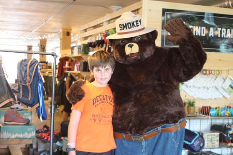 Megan Broome/The Clayton Tribune. Wiley Perreault, 10, poses with Smokey Bear at Wander North Georgia on Monday. Representatives of the Georgia Forestry Commission walked around downtown Clayton to educate the community on fire risk during a drought and how to prevent wildfires. 