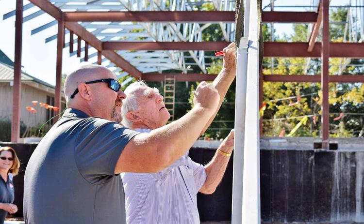 Cornelia City Manager Donald Anderson, left, and Cornelia Mayor James C. “J.C.” Irby ink their signatures on the final beam before it’s placed atop the city’s new municipal complex during a topping-out ceremony Friday, Sept. 6, at the site. (Photo/CHAMIAN CRUZ)