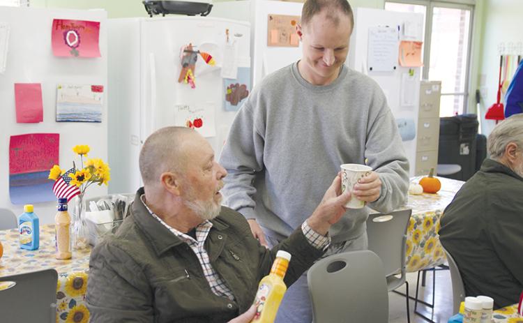 Michael Parks, right, brings a beverage to Bruce Fry of Clarkesville at the Clarkesville Soup Kitchen on Monday afternoon.