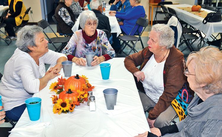 Karen Katz, Patsy Edwards, Barbara Land and JoAnn Cross (clockwise from left) converse just before the Thanksgiving meal at the Habersham County Senior Center on Friday. The friends were part of a record crowd at the meal with more than 140 guests.