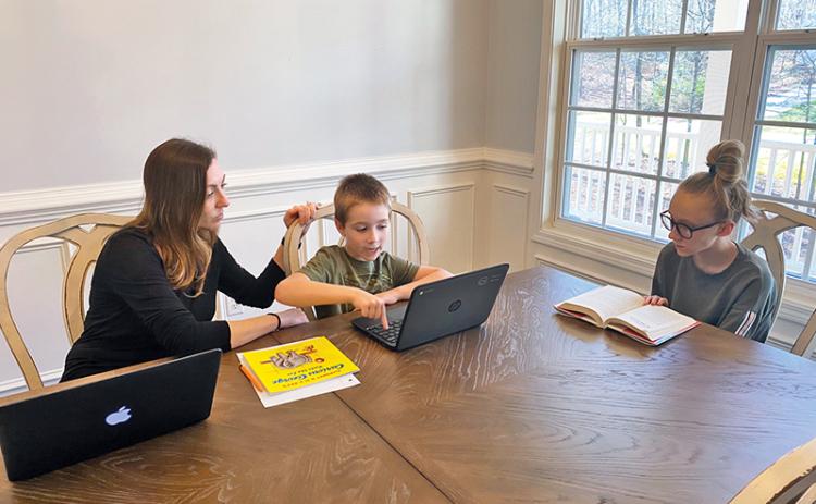 Clarkesville Elementary teacher April Jones helps her children Zachary, 7, and Corie, 12, work on their school assignments from home. Jones teaches her second graders remotely as well during a busy daily routine.