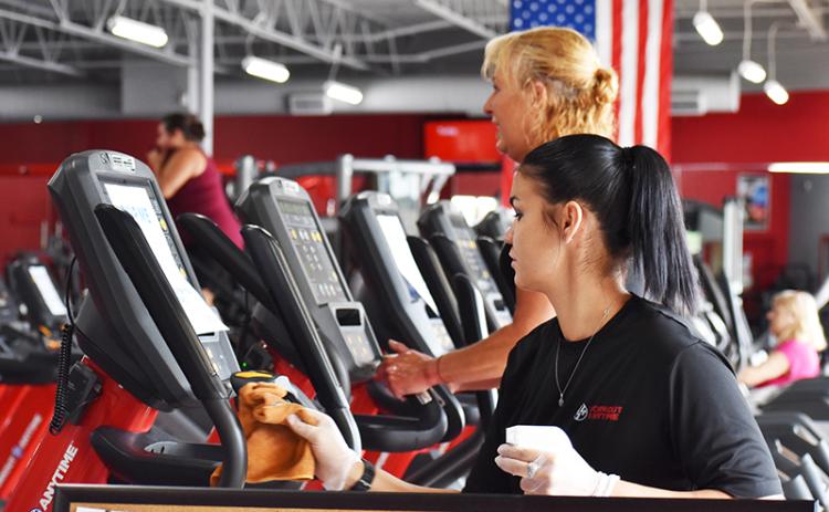 Ariel Coones, a trainer at Workout Anytime in Cornelia, sanitizes one of the many ellipticals. The staff plans to regularly clean the gym equipment now that members have returned.