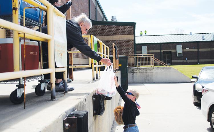 Demorest Elementary School nutritionist Mary Edder hands out meals to McCoy Wilson during Wednesday’s lunch pickup. Photo by Eric Pereira