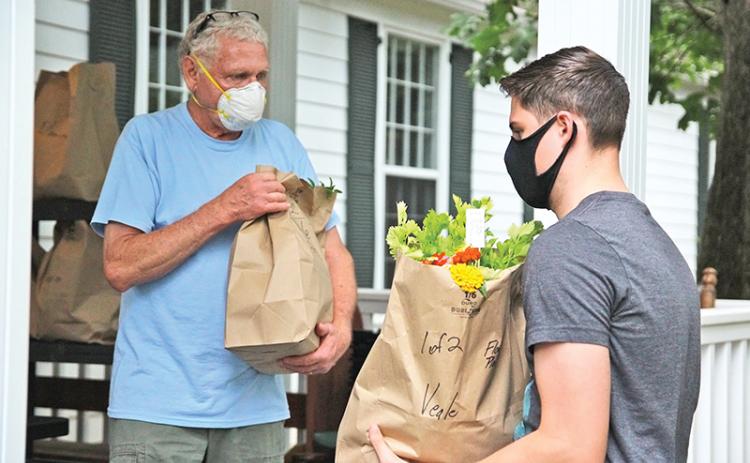 Carson Veale (right) from Clarkesville picks up his Northeast Georgian  Locally Grown produce with the assistance of volunteer Tom Gagnon. Locally grown foods have seen a surge during the pandemic crisis.