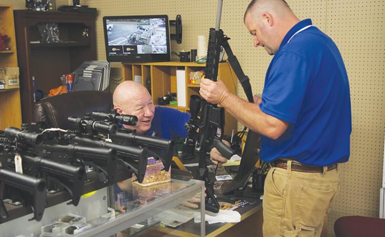 Country Boy Sports owner Kerry Stephens assists customer Kipp Dowdy with the purchase of his new rifle.