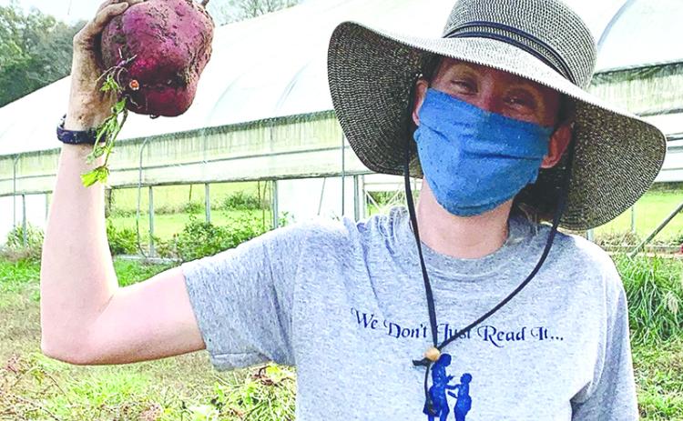 Melon Head Farm Manager Emma Courson shows off a giant sweet potato. Photo courtesy of Joni Kennedy