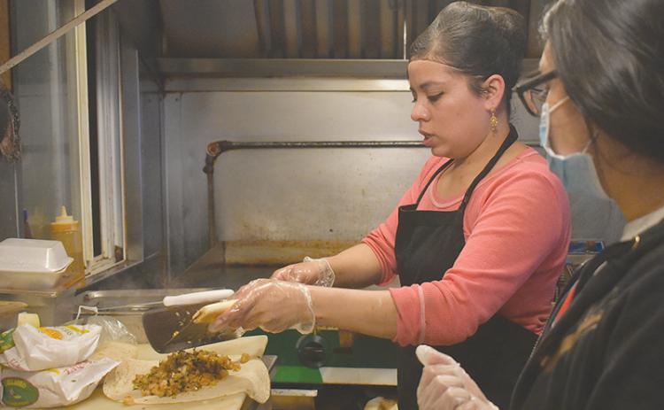 El Carreton Co-Owner Marisela Gonzalez and Jennifer Martinez prepare a shrimp burrito for a takeout order Tuesday evening in Cornelia.