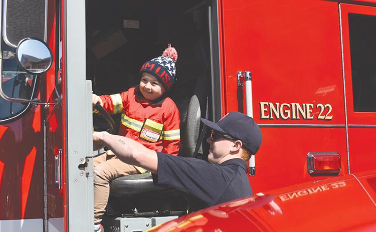 Four-year-old Sawyer Stille takes the opportunity while he’s dressed as a firefighter to honk a real fire truck at the new Cornelia South Station on Saturday.