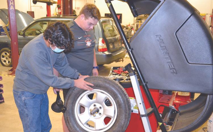 Habersham Central student Landen LaPrade (right) and Carlos Mora check the balance of a tire on a new machine added to the school’s automotive workshop Wednesday. MATTHEW OSBORNE/Staff