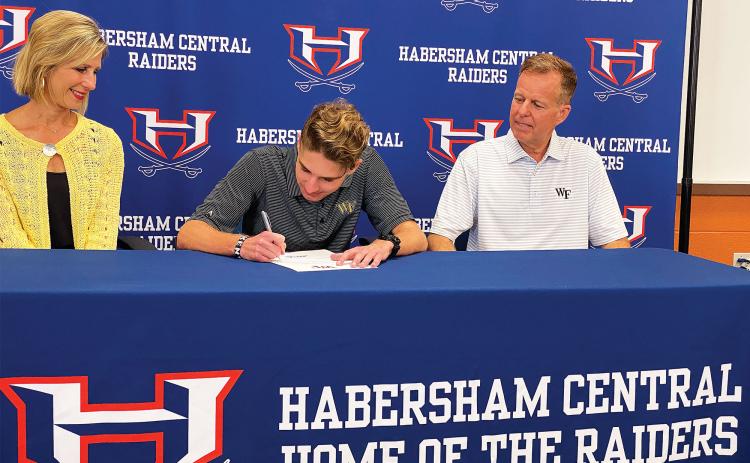 Andrew Kivett (center) signed his national letter of intent last Thursday to run track and cross country at Wake Forest. Pictured with him are his parents Luci (left) and Ed (right) Kivett. ISAIAH SMITH/Staff