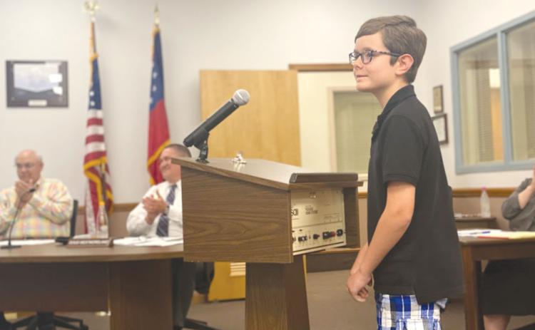 Erik Jordan, a fourth-grade student at Woodville Elementary School, read his award-winning poem to the Habersham County Board of Education on Monday, to the delight of board members Robert Barron and Doug Westmoreland. CHAMIAN CRUZ/Staff