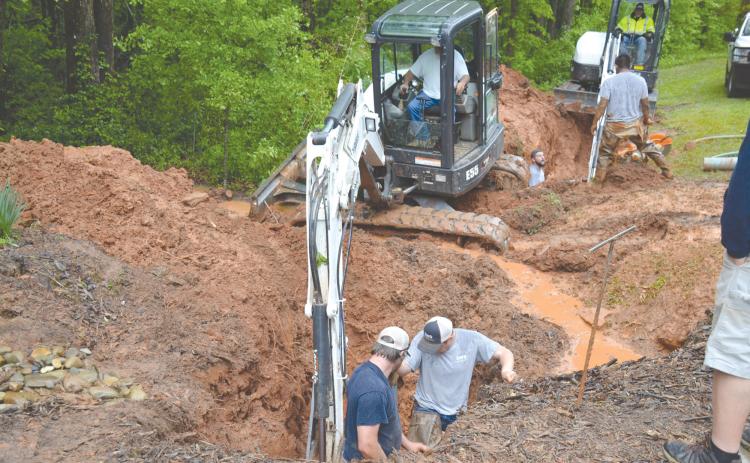 Workers from Demorest’s water department look to repair the pipe damaged Tuesday morning by a freak lightning strike that melted at least one section of a water pipe (inset) and left a trench through the woods. MATTHEW OSBORNE/Staff