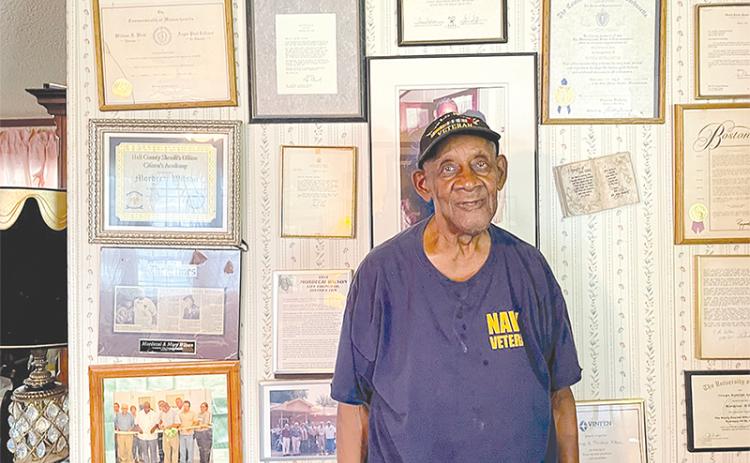 Mordecai Wilson stands by the many awards that adorn the wall of his Lula home.