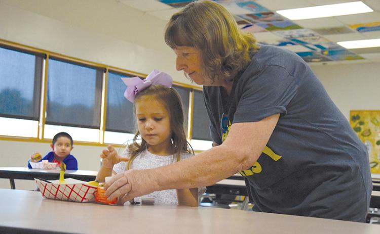 Above, Clarkesville Elementary custodian JoAnn Oliver helps kindergartener Lily Ellison get her breakfast. SAMANTHA SINCLAIR/CNI News Service
