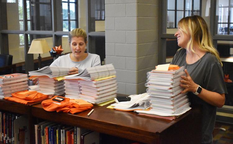 Habersham Central teachers Kelli Holland and Dr. Kathleen Addison pick up their first day packets and shirts in the media center Monday afternoon. School starts for students Friday. MATTHEW OSBORNE/Staff