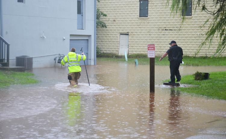 Cornelia first responders wade through a flooded parking lot outside of  Structure Hair Studio in Cornelia on Tuesday afternoon. BRIAN WELLMEIER/Staff