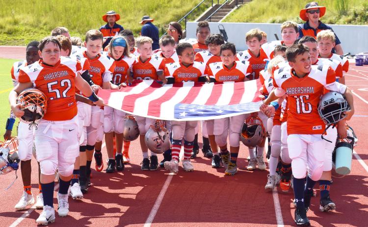 Habersham’s 10U football team members carry out an American flag before their game Saturday in honor of the 9/11 anniversary. MATTHEW OSBORNE/Staff