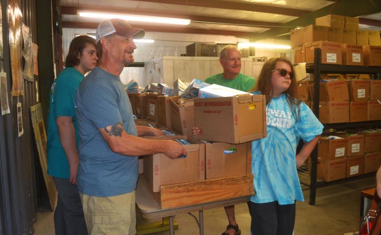 From left, volunteers Micah Hunnicutt, Gary Burton, Rick Chaffin and Austin Clarke prepare to deliver food to families Wednesday night. BRIAN WELLMEIER/Staff